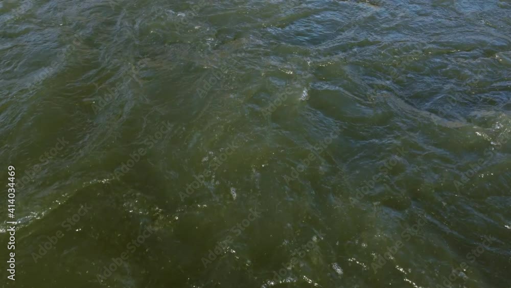 Top view of the turbulent surface of the water. The waves are churning, the river rushing, the place next to the waterfall.