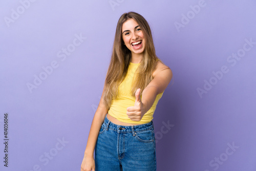 Young woman over isolated purple background with thumbs up because something good has happened