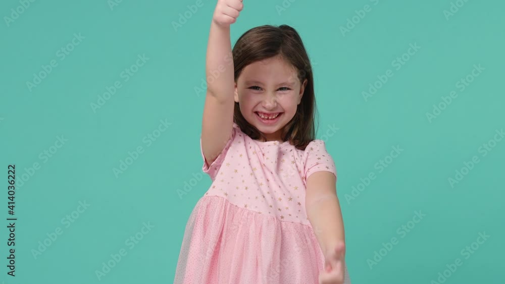 Little toothy smiling cheery cute kid girl 5-6 years old wears pink dress have fun show like isolated on pastel blue background child studio portrait. Mother's Day love family people lifestyle concept Little toothy smiling cheery cute kid girl 5-6 years old wears pink dress have fun show like isolated on pastel blue background child studio portrait. Mother's Day love family people lifestyle concept