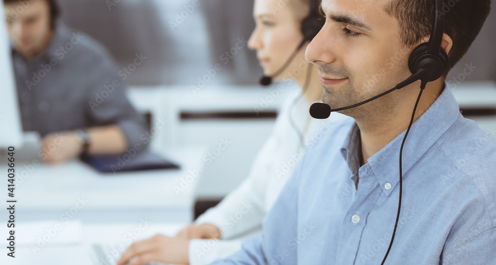 Call center. Group of casual dressed operators at work. Adult businessman in headset at customer service office. Telesales in business Call center. Group of casual dressed operators at work. Adult businessman in headset at customer service office. Telesales in business