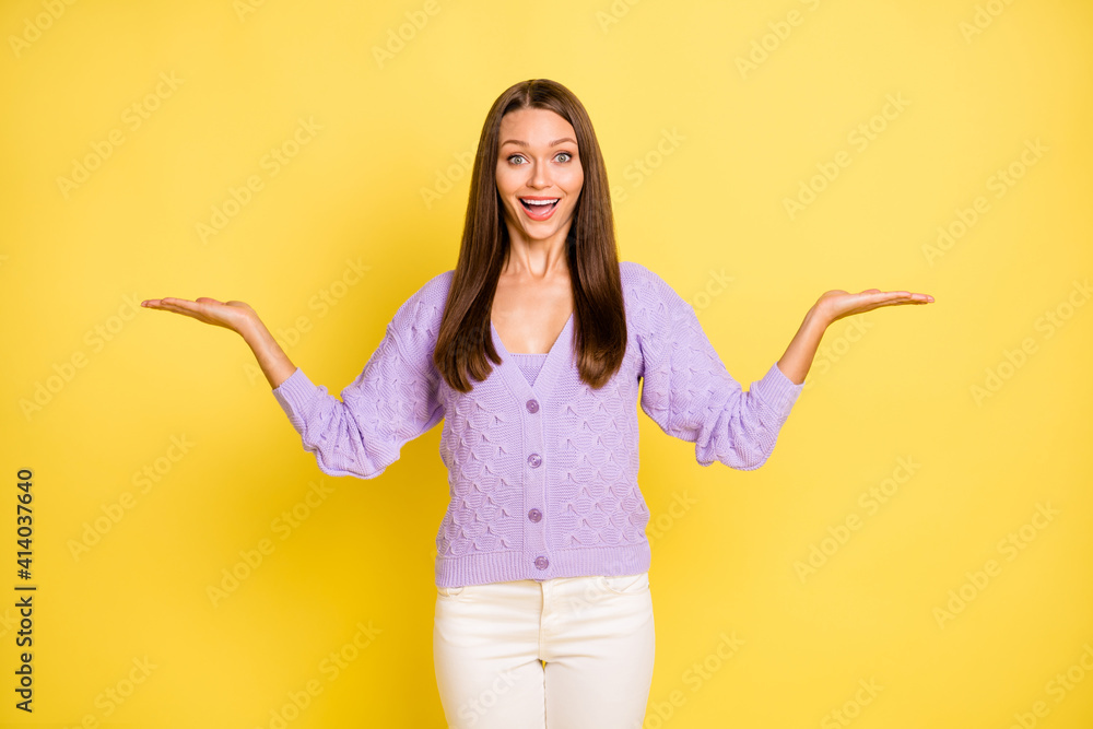 Portrait of amazed lovely cheerful girl holding on palms two variants copy empty space isolated over bright yellow color background Portrait of amazed lovely cheerful girl holding on palms two variants copy empty space isolated over bright yellow color background