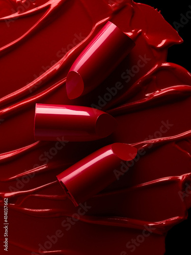 Broken red lipsticks over smudged lipstick background