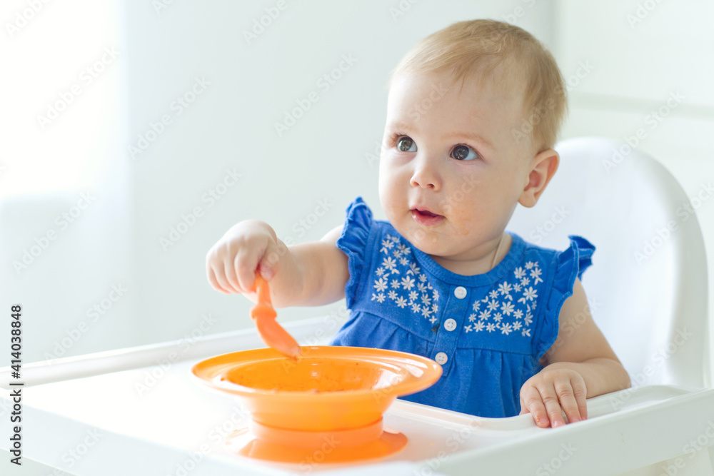 A small child in a high chair feeds himself. High quality photo. A small child in a high chair feeds himself. High quality photo.