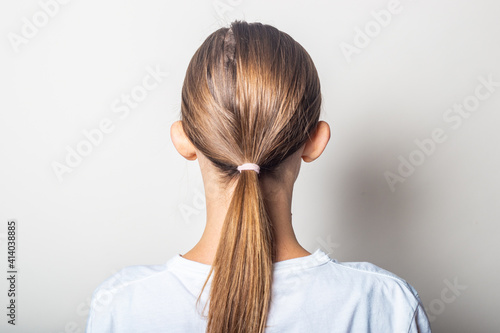 Girl with protruding ears, back view on a light background. photo