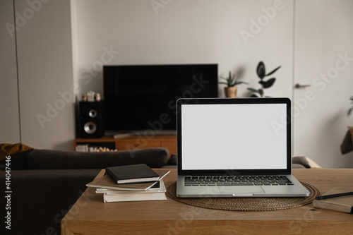 Laptop with blank copy space screen on table with notebooks on wooden table. Minimalist home office workspace. Mockup template.