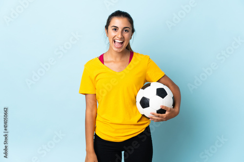 Young hispanic football player woman over isolated on blue background with surprise facial expression © luismolinero