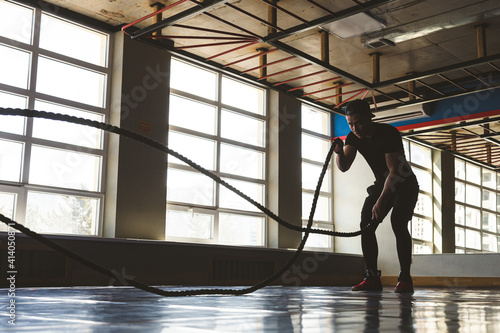 Crossfit with ropes. The athlete is training in the gym. Silhouette photography