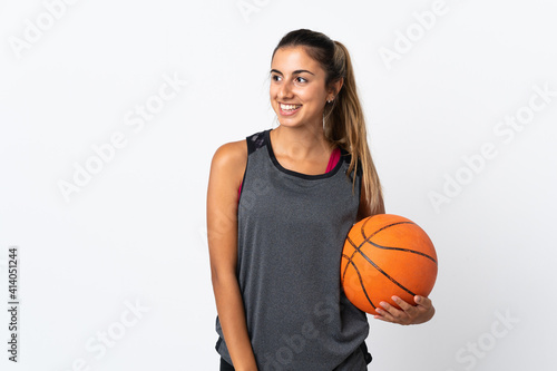 Young hispanic woman playing basketball over isolated white background looking to the side and smiling