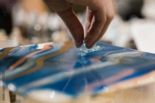 at the workshop on creating fluid art transparent crystals are poured onto the blue resin art picture