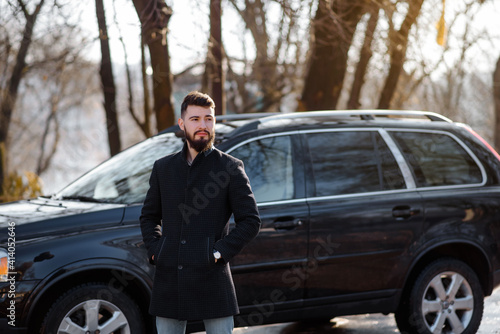 Portrait of bearded stylish young handsome man in black coat outside. © Med Photo Studio