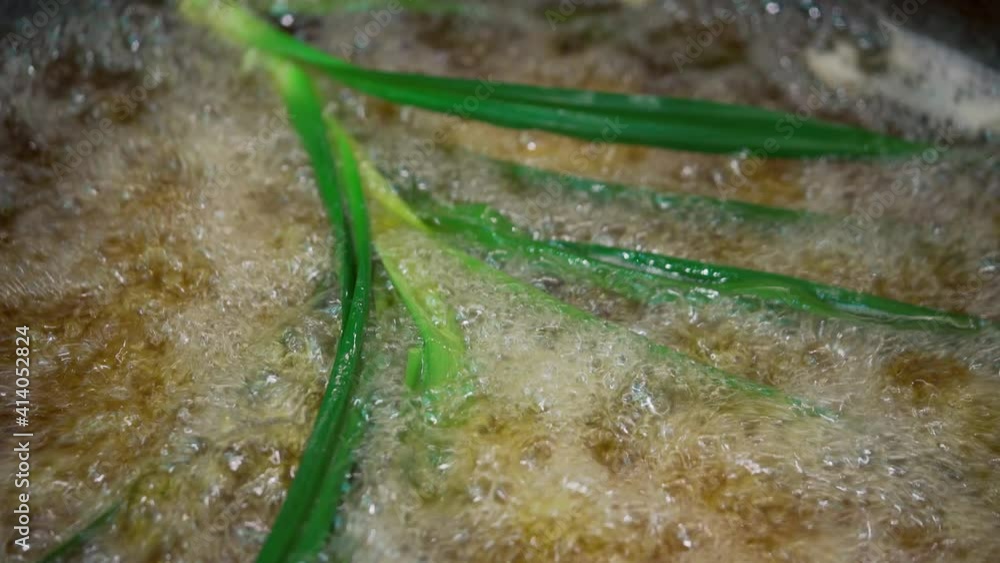Closeup boiling oil fried food. Cooking frying pandan leaf in hot pot with Palm oil. Closeup boiling oil fried food. Cooking frying pandan leaf in hot pot with Palm oil.