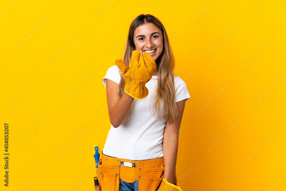 Young hispanic electrician woman over isolated yellow wall inviting to come with hand. Happy that you came Young hispanic electrician woman over isolated yellow wall inviting to come with hand. Happy that you came