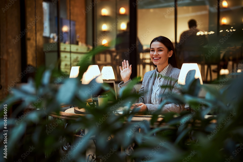 Delighted brunette female person welcoming her colleagues