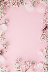 Happy Easter frame with flowers, feathers and egg shells on pink background