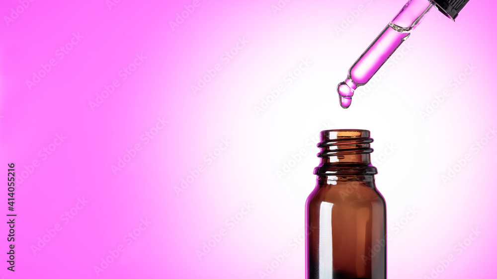 Oily drop falls from a cosmetic pipette, isolated on pink background Oily drop falls from a cosmetic pipette, isolated on pink background