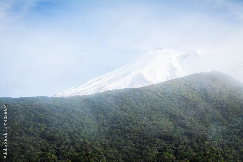Low clouds hovering over mountain ridge and snow covered peaks. Natural background