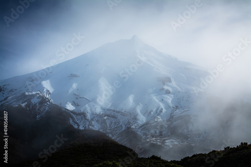 Magnificent snow covered cone of Mt Taranaki is barely visible in thick fog. Mt Egmont National Park  New Zealand