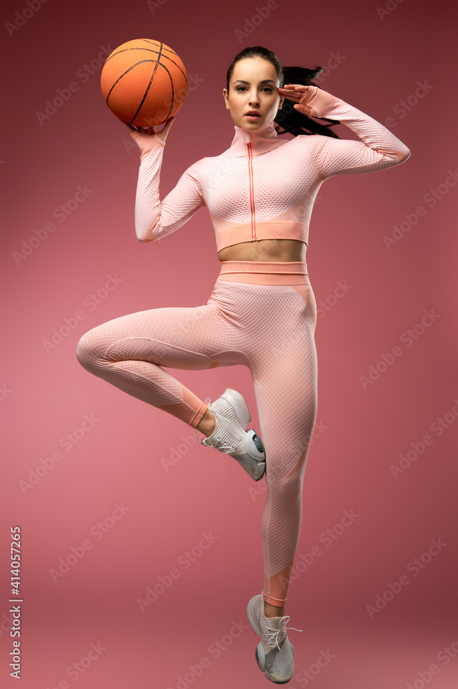 Charming young woman with basketball ball jumping in the air Charming young woman with basketball ball jumping in the air