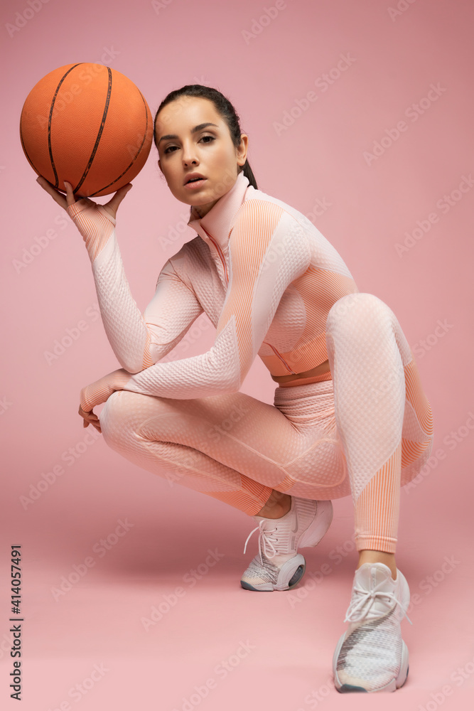 Sporty woman with basketball ball crouching down in studio Sporty woman with basketball ball crouching down in studio