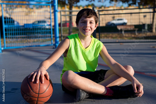 Young basketball player sitting on the court wearing a yellow sleeveless © Rafa Fernandez