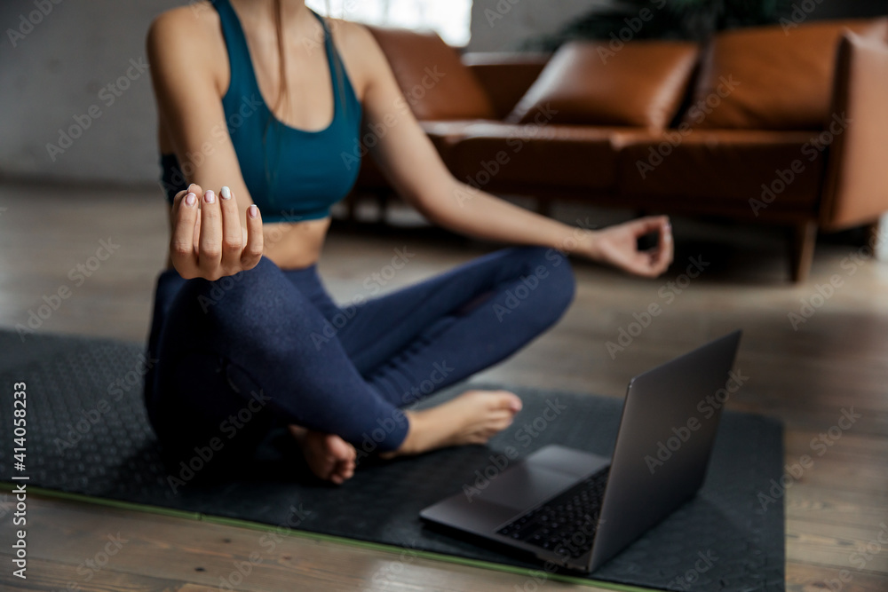 Naklejka premium Sporty fit slim woman coach do practice video online meditate Sukhasana posture. High quality photo