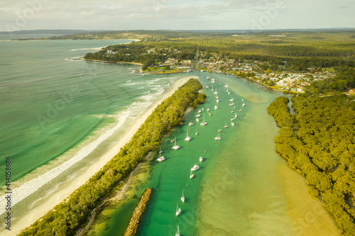 Aerial view of a small boats fleet sailing the Currambene creek at sunset, Huskisson, New South Wales, Australia. photo