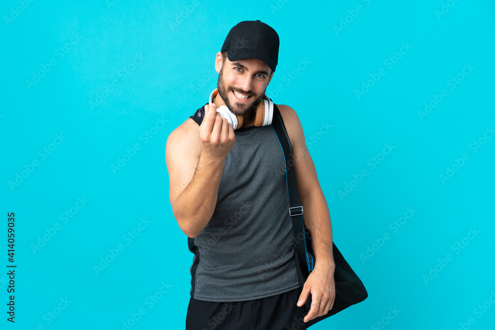 Young sport man with sport bag isolated on blue background making money gesture
