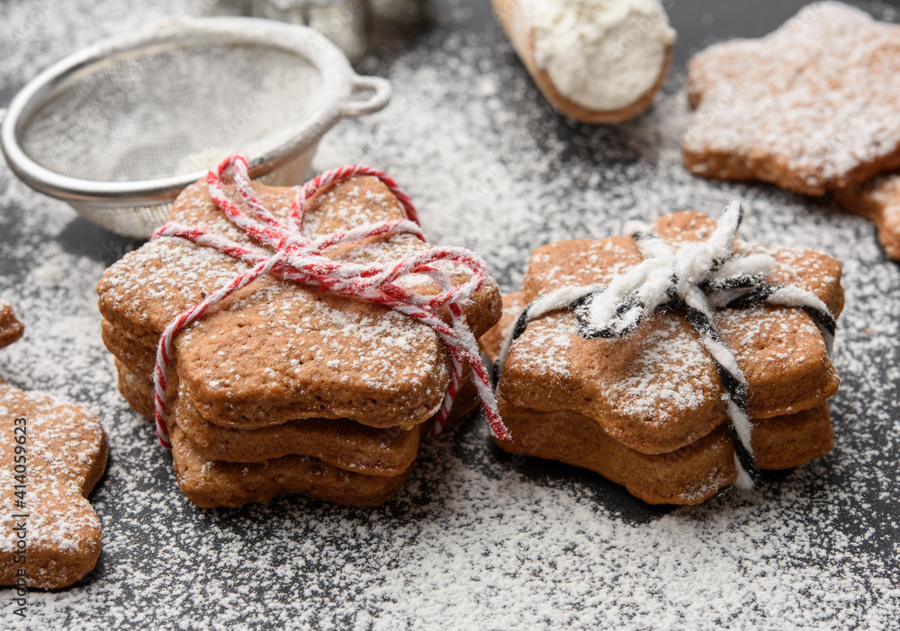 Star shaped baked gingerbread cookies sprinkled with powdered sugar on a black table Star shaped baked gingerbread cookies sprinkled with powdered sugar on a black table