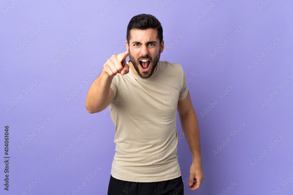 Young handsome man with beard over isolated background frustrated and pointing to the front