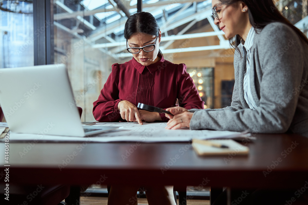 Fototapeta premium Concentrated Asian female person pointing at drawing
