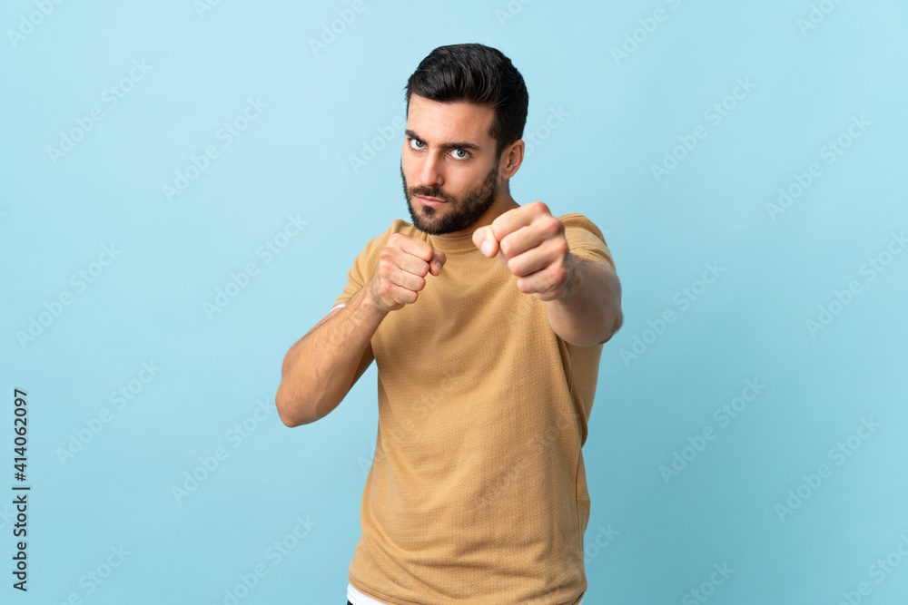 Naklejka premium Young handsome man with beard over isolated background with fighting gesture