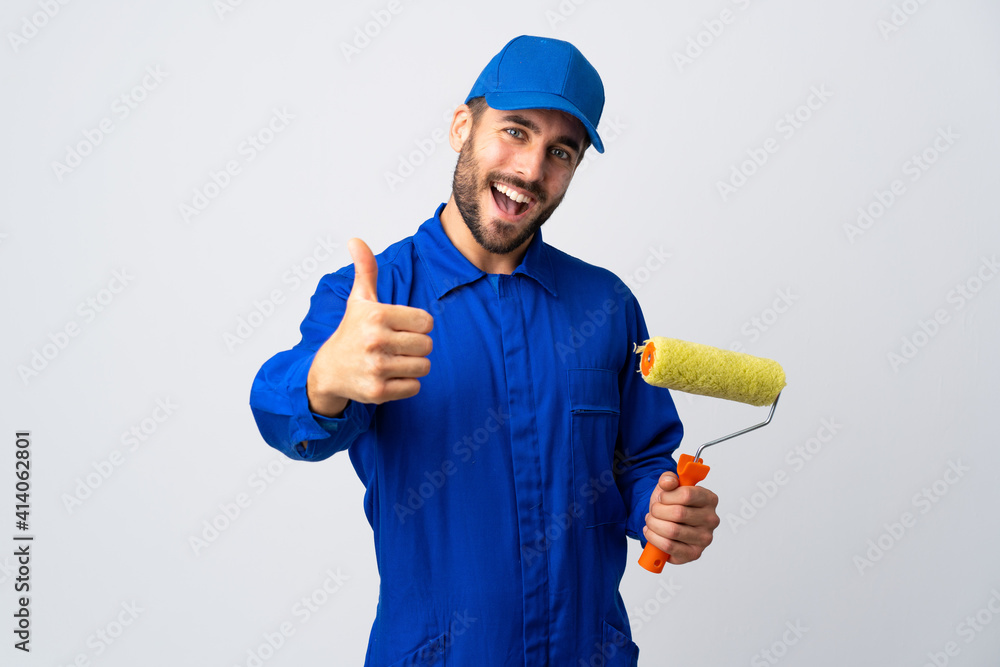 Painter man holding a paint roller isolated on white background with thumbs up because something good has happened