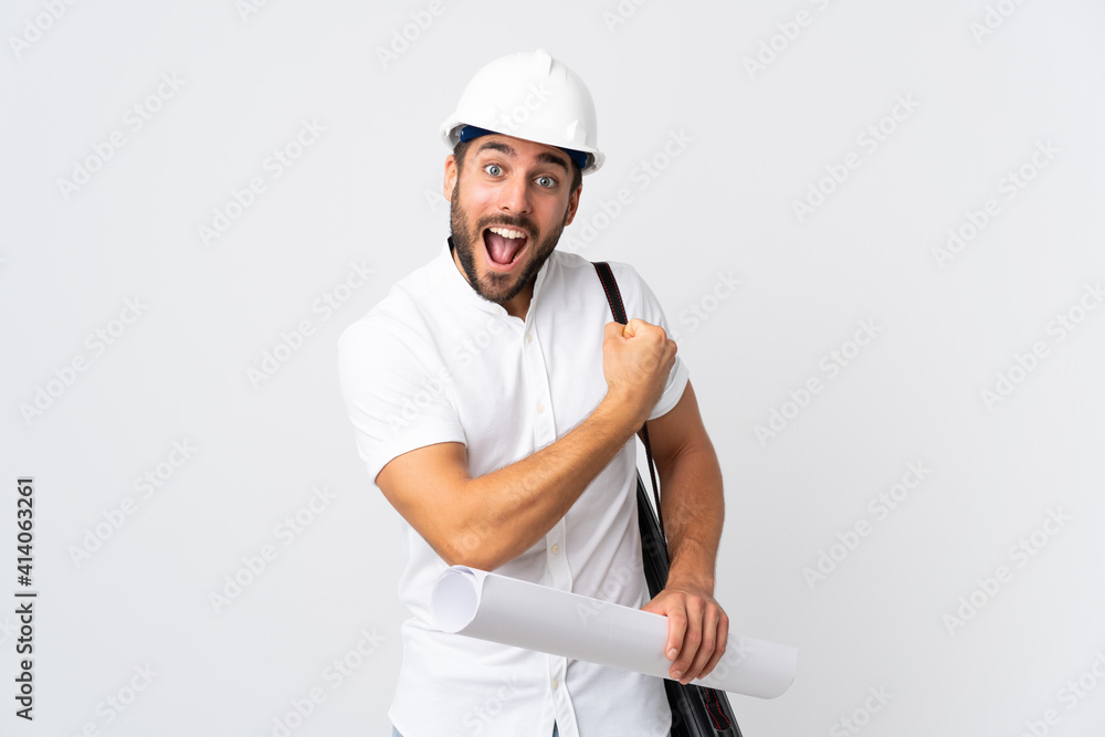 Young architect man with helmet and holding blueprints isolated on white background celebrating a victory Young architect man with helmet and holding blueprints isolated on white background celebrating a victory
