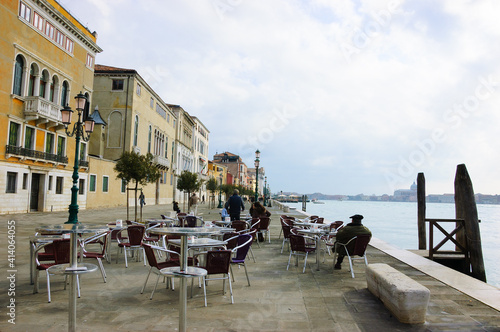 Venice, Italy. People (unrecognizable; back view) relaxing in an open-air cafe at Zattere promenade in Dorsoduro district and admiring a view of a lagoon. Everyday Venice life.  photo