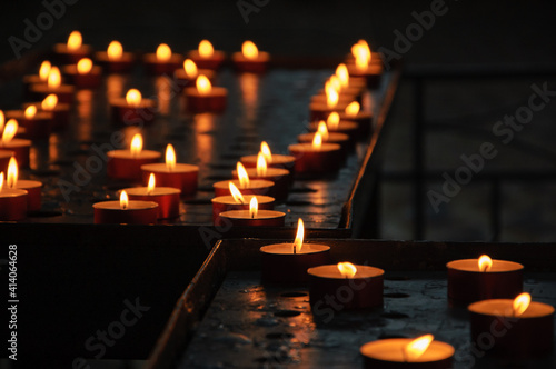 Burning candles in dark church. Golden flame glow. Reflection. Religious background.