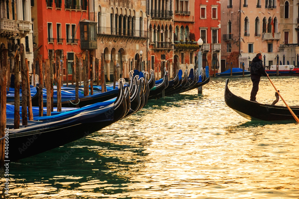 Venice, Italy. Gondola with unrecognizable gondolier departing from the pier. Romantic landscape.