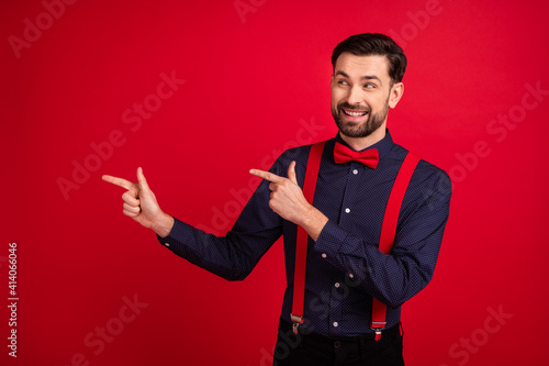 Photo of young handsome cheerful smiling gentleman point finger copyspace advertisement isolated on red color background © deagreez