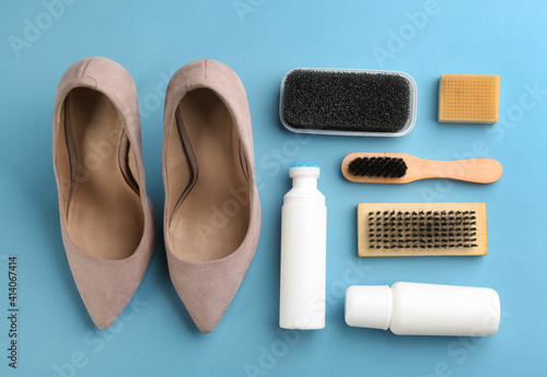 Stylish footwear with shoe care accessories on light blue background, flat lay