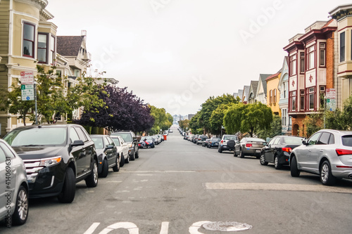 Horizontal shot of a beautiful street with trees  parked cars and classic San Francisco houses on both sides  California - United States of America aka USA