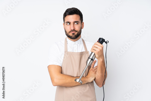 Man using hand blender isolated on white background thinking an idea