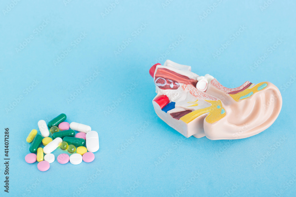 a handful of pills and an ear mock on a blue background. Acute otitis