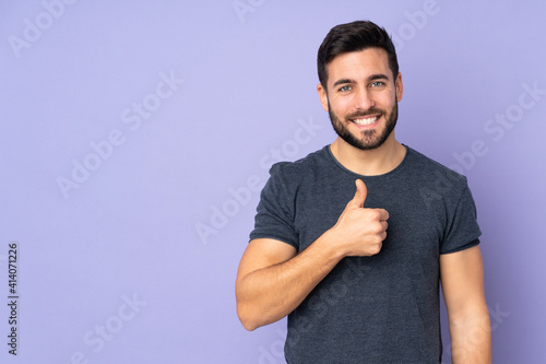 Caucasian handsome man giving a thumbs up gesture over isolated purple background photo