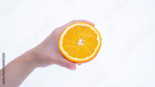 A woman's hand holds a ripe orange in her palm. Orange fruit in hand Isolated on white background