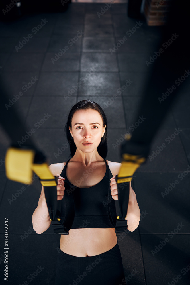 Determined female doing pull ups with straps