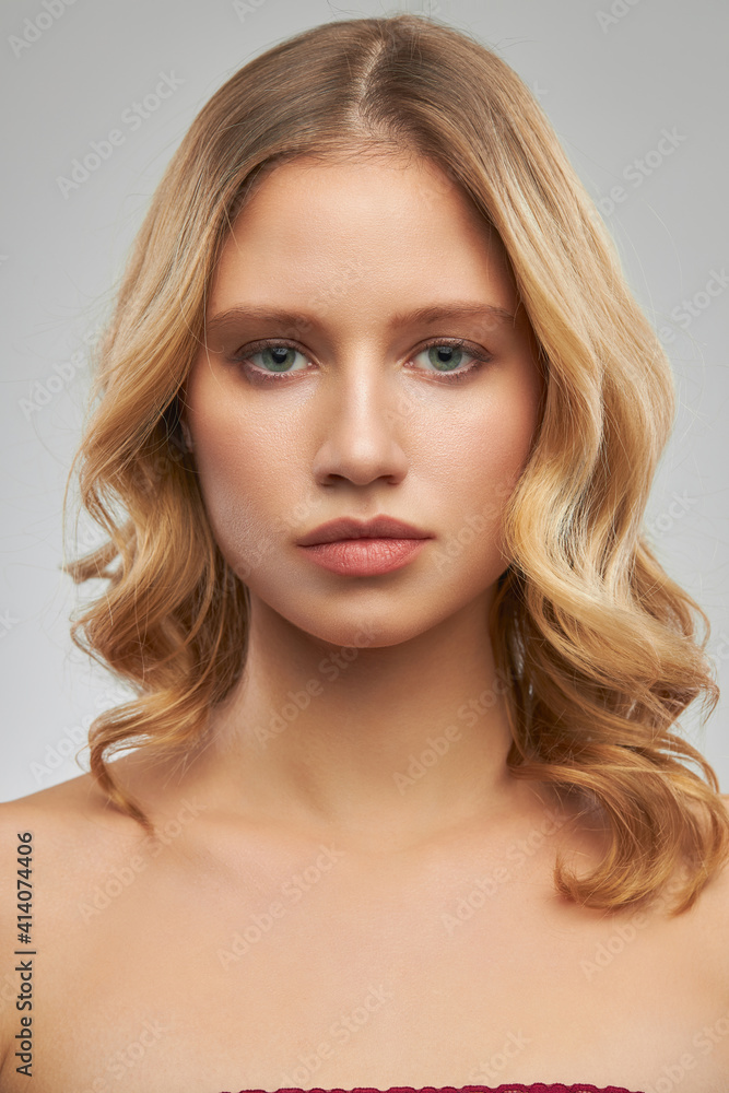 Cute blonde without makeup with clear and curly hair standing in studio and posing. Cute blonde without makeup with clear and curly hair standing in studio and posing.