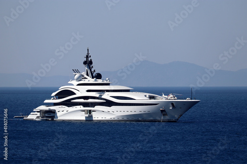 Luxury yacht with helipad and helicopter sailing in a sea, side view. White futuristic boat on mountain island background © Oleg