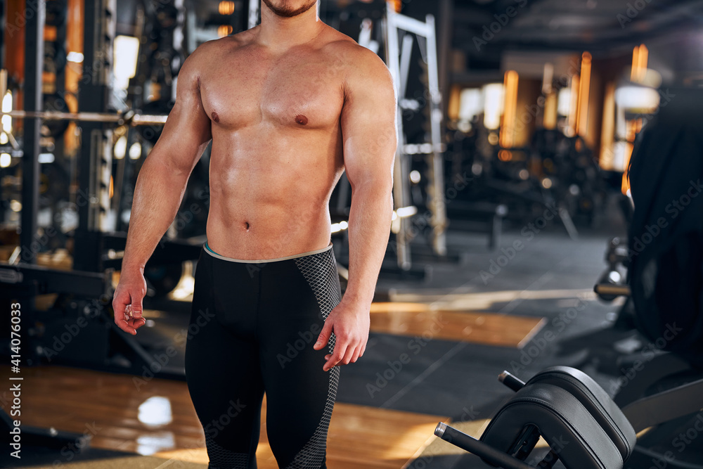 Naklejka premium Handsome topless male bodybuilder coming to gym