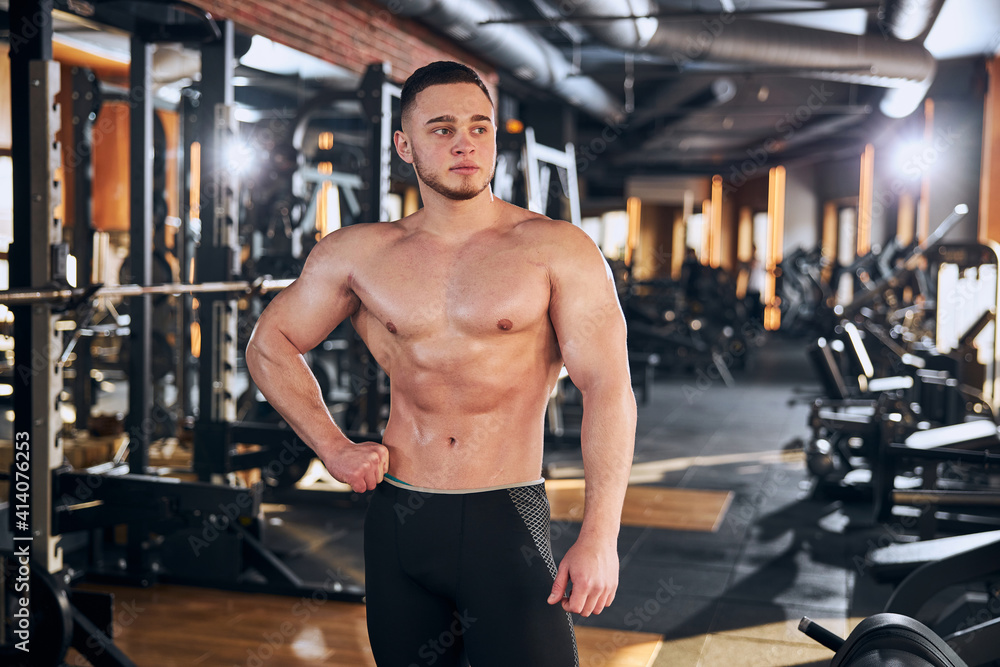 Naklejka premium Handsome muscular guy spending time in gym