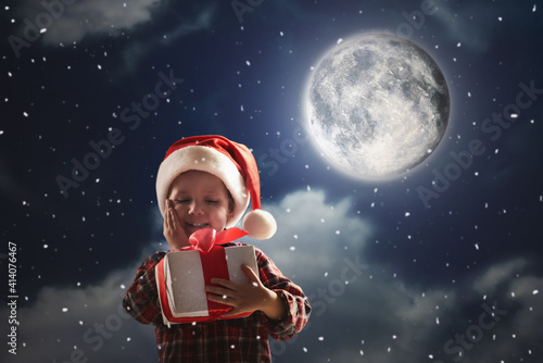 Cute little boy with Christmas gift on full moon night. Waiting for Santa Claus © New Africa