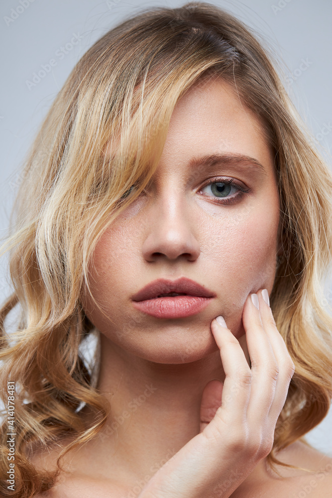 Cute blonde without makeup with clear and curly hair standing in studio and posing. Cute blonde without makeup with clear and curly hair standing in studio and posing.